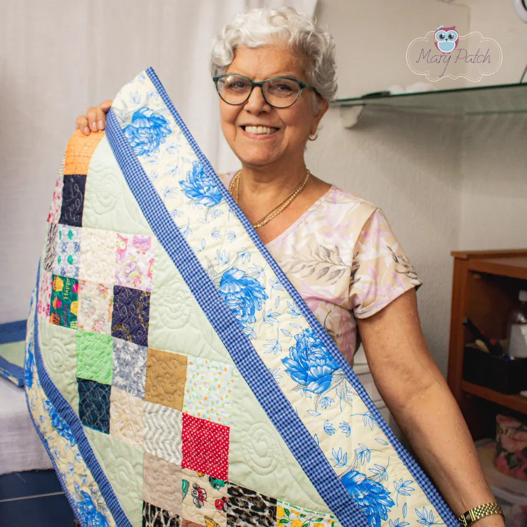 Mary mostrando uma colcha de patchwork feita com retalhos